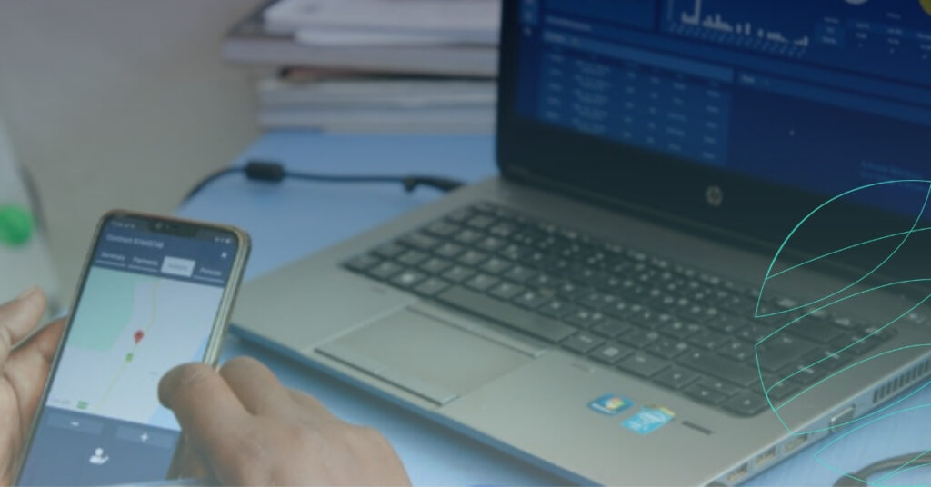 A person using a mobile app with a location map on their smartphone next to an open laptop displaying data analytics, illustrating Upya´s digital tools for field operation management.